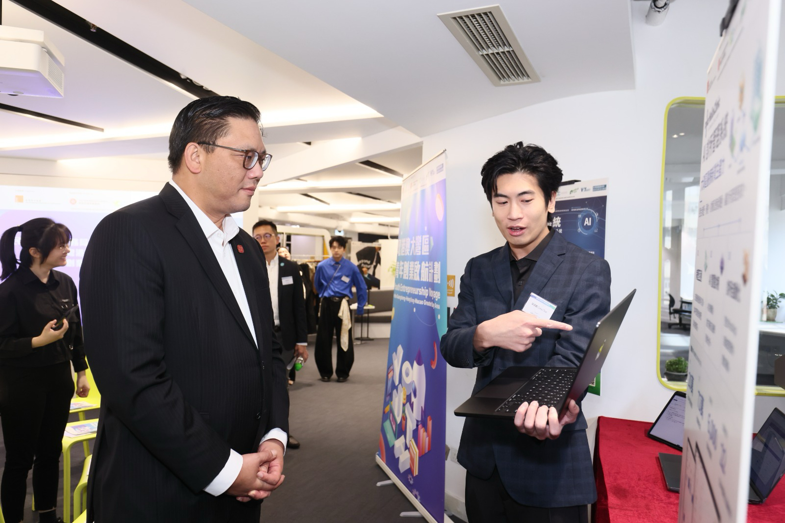 A HelloClinic colleague using a laptop to demonstrate the clinic management system to Clarence Leung